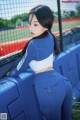 A woman in a blue and white outfit leaning against a fence.