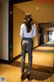 A woman in a white shirt and gray pants walking down a hallway.