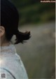 A woman with her hair in a ponytail standing in a field.