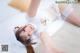 A woman laying on top of a bed in a white dress.