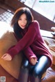 A woman sitting on top of a brown couch.