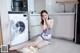 A woman sitting on the floor in front of a washing machine.