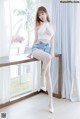 A woman sitting on top of a wooden table next to a window.