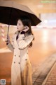 A woman in a trench coat holding an umbrella.