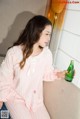 A woman sitting on a couch holding a bottle of beer.