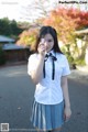 A woman in a school uniform holding a flower in her hand.