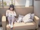 A woman sitting on a couch in front of a window.