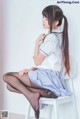 A woman sitting on a white chair wearing black stockings.