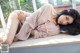 A woman laying on a window sill in a pink robe.