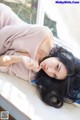 A woman laying on a window sill with her hand on her chin.