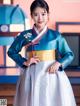 A woman in a blue and white hanbok posing for a picture.