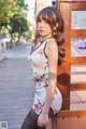 A woman in a white dress leaning against a wooden fence.