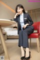 A woman in a business suit sitting on a red chair.