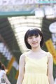 A young woman in a yellow dress smiles at the camera.