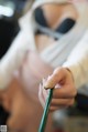 A woman in a white robe holding a green pencil.