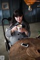 A woman sitting at a table holding a cup of coffee.