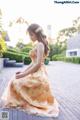 A woman in a long dress sitting on a brick walkway.