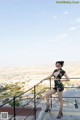 A woman in a black dress standing on a balcony.