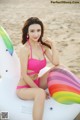 A woman in a pink bikini sitting on an inflatable unicorn.