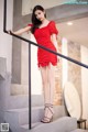 A woman in a red dress is standing on some stairs.