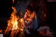 A woman sitting next to a fire in the dark.