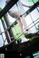 A woman in a white dress is standing on a rope bridge.