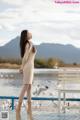 A woman standing on a wooden dock next to a body of water.