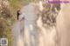 A woman in a beige dress standing on a dirt road.