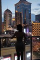 A woman standing on a balcony looking out over a city.