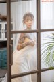 A woman in a wedding dress standing in front of a window.