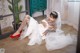 A woman in a wedding dress and red shoes sitting on the floor.