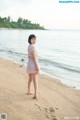 A woman in a pink dress standing on a beach.