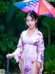 A woman in a kimono holding an umbrella in the rain.