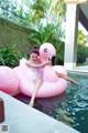 A woman sitting on an inflatable flamingo floating in a pool.