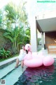 A woman in a white bathing suit standing next to a pink flamingo.