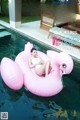 A woman laying on an inflatable flamingo floating in a pool.