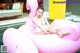 A woman sitting on a pink flamingo floating in a pool.