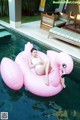 A woman laying on an inflatable flamingo floating in a pool.